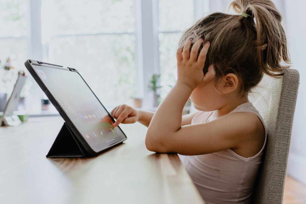 Girl sitting bored in front of a tablet