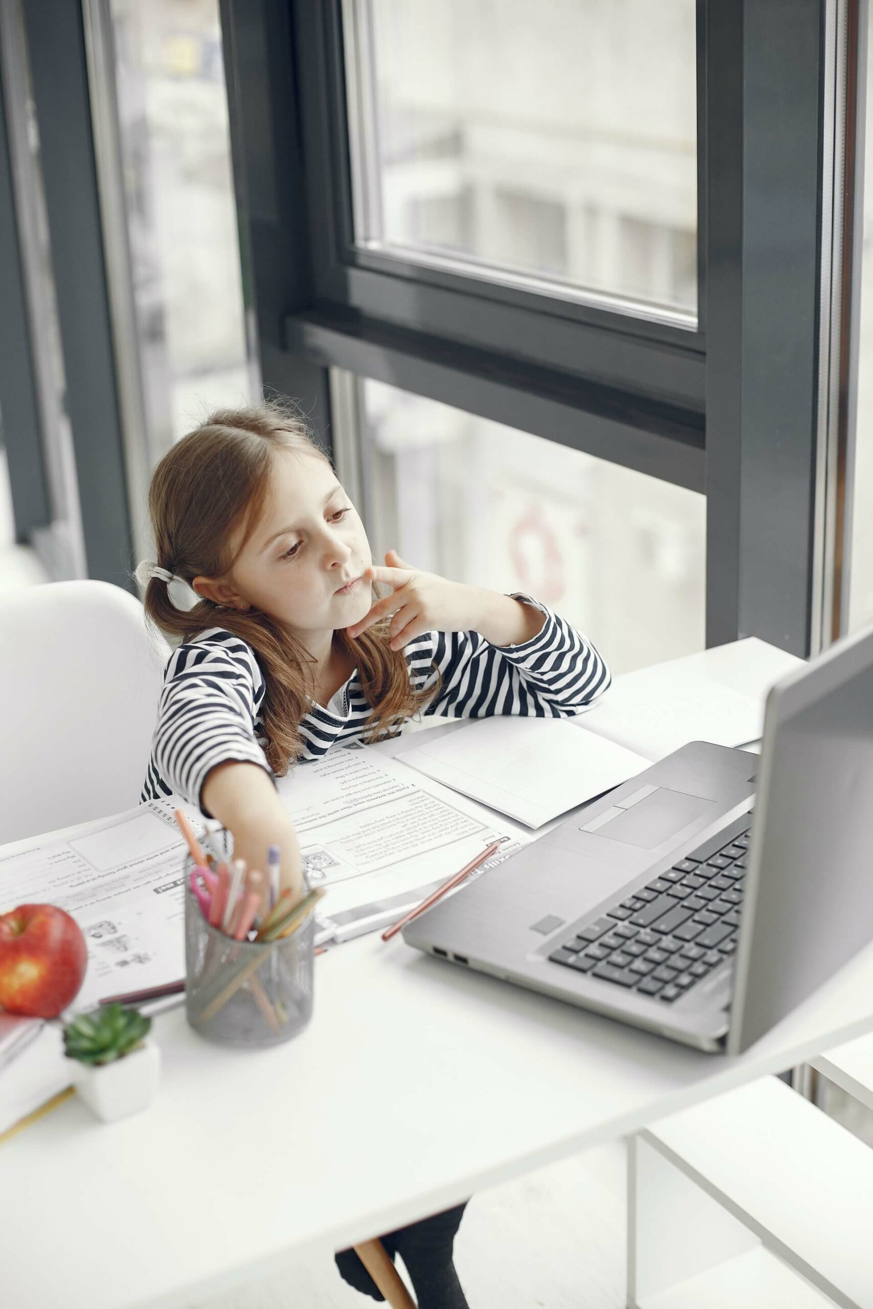 A young child sitting at a laptop undergoing homeschooling