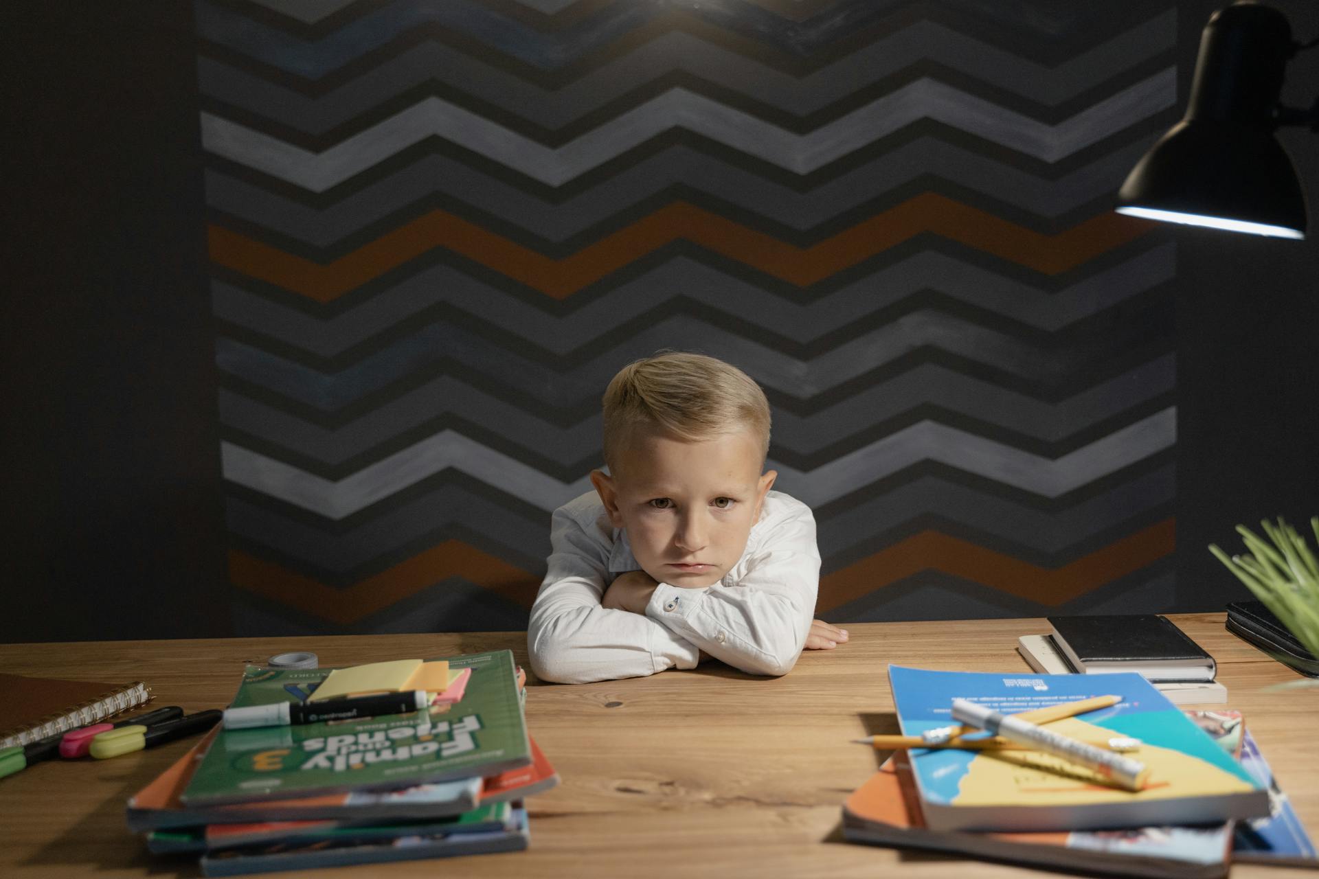 A distraught child sitting in front of excessive homework they must complete